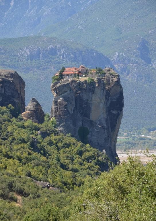 A narrow sandstone pillar with a monastery in the Meteora landscape