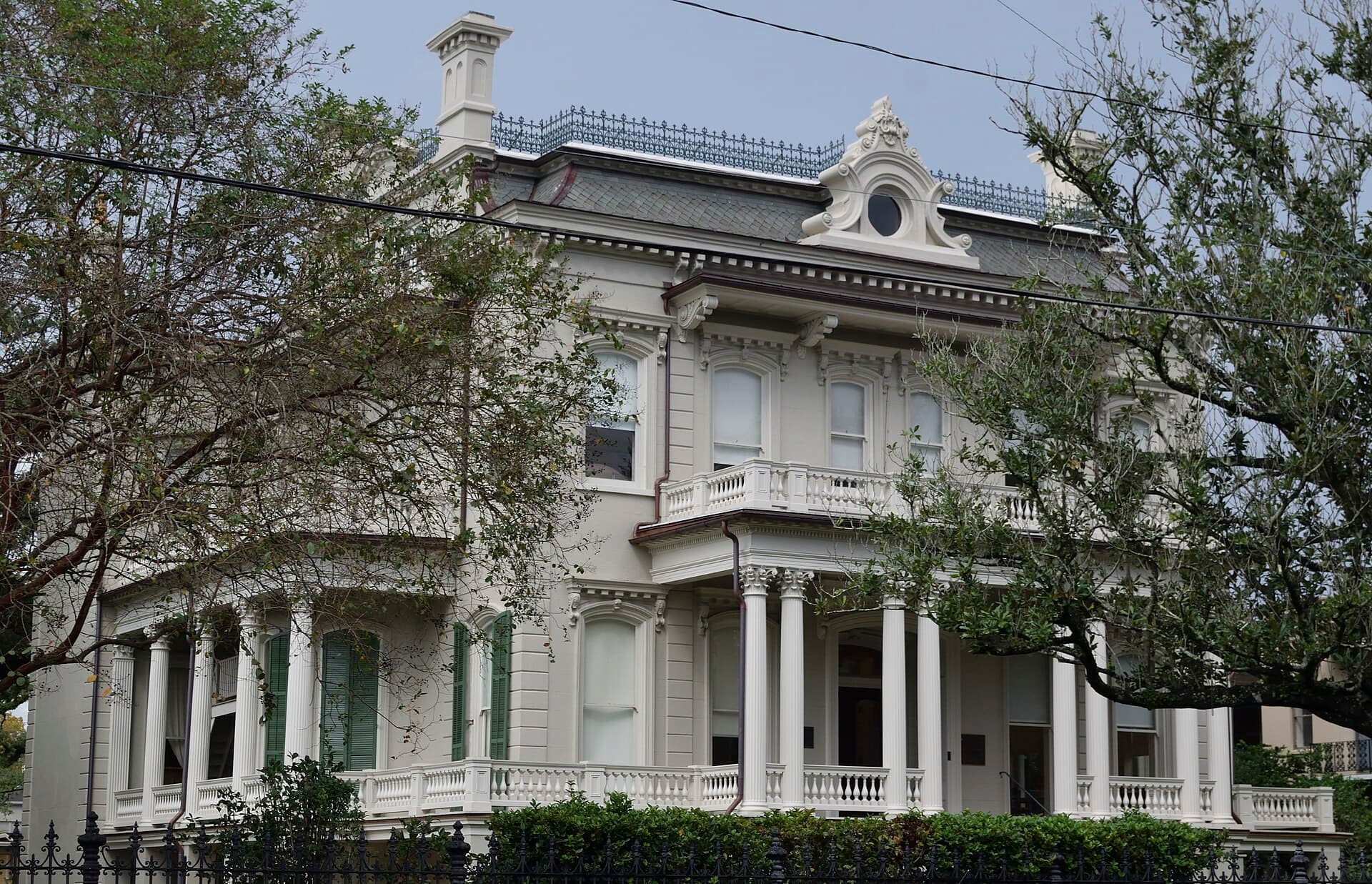 Columned historic mansion behind a cast-iron fence in the Garden District