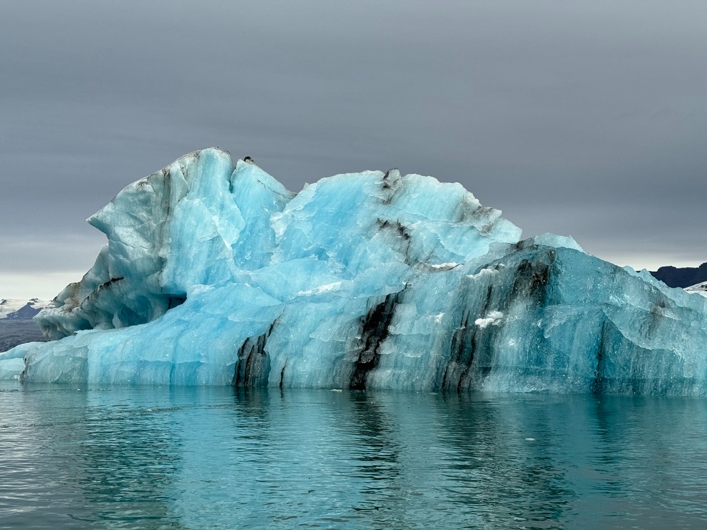 A vivid blue iceberg reflected in the water at Jökulsárlón Glacier Lagoon