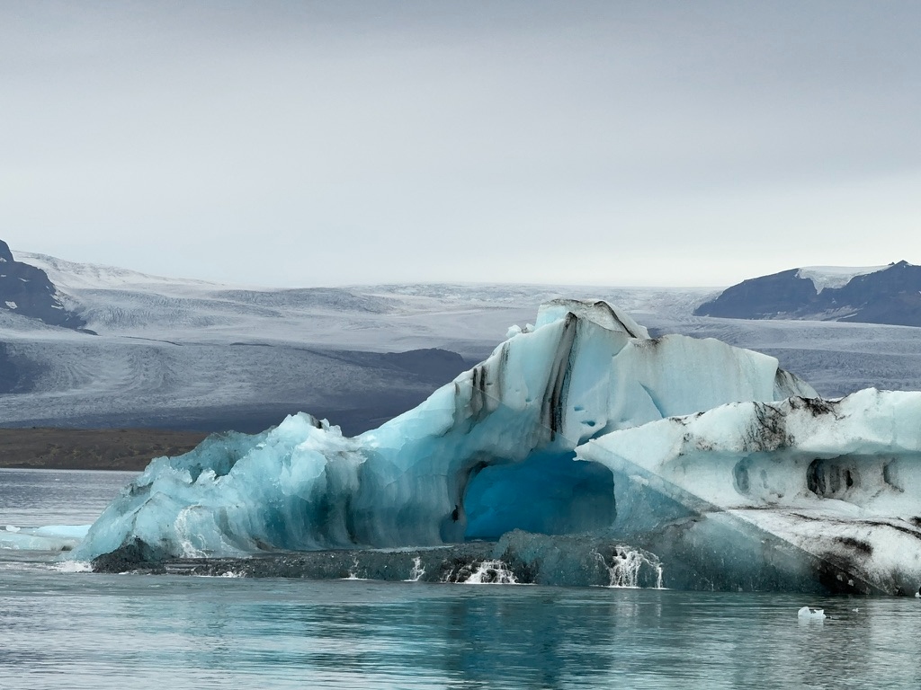 A blue iceberg floating in Jökulsárlón Glacier Lagoon with the glacier behind it