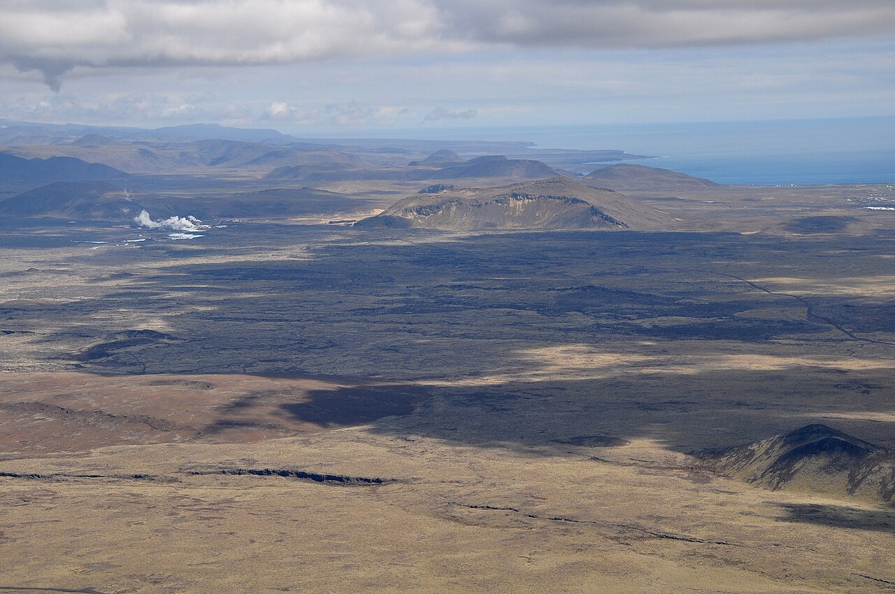 Black lava fields across the Reykjanes Peninsula with steam rising from the Svartsengi geothermal power station