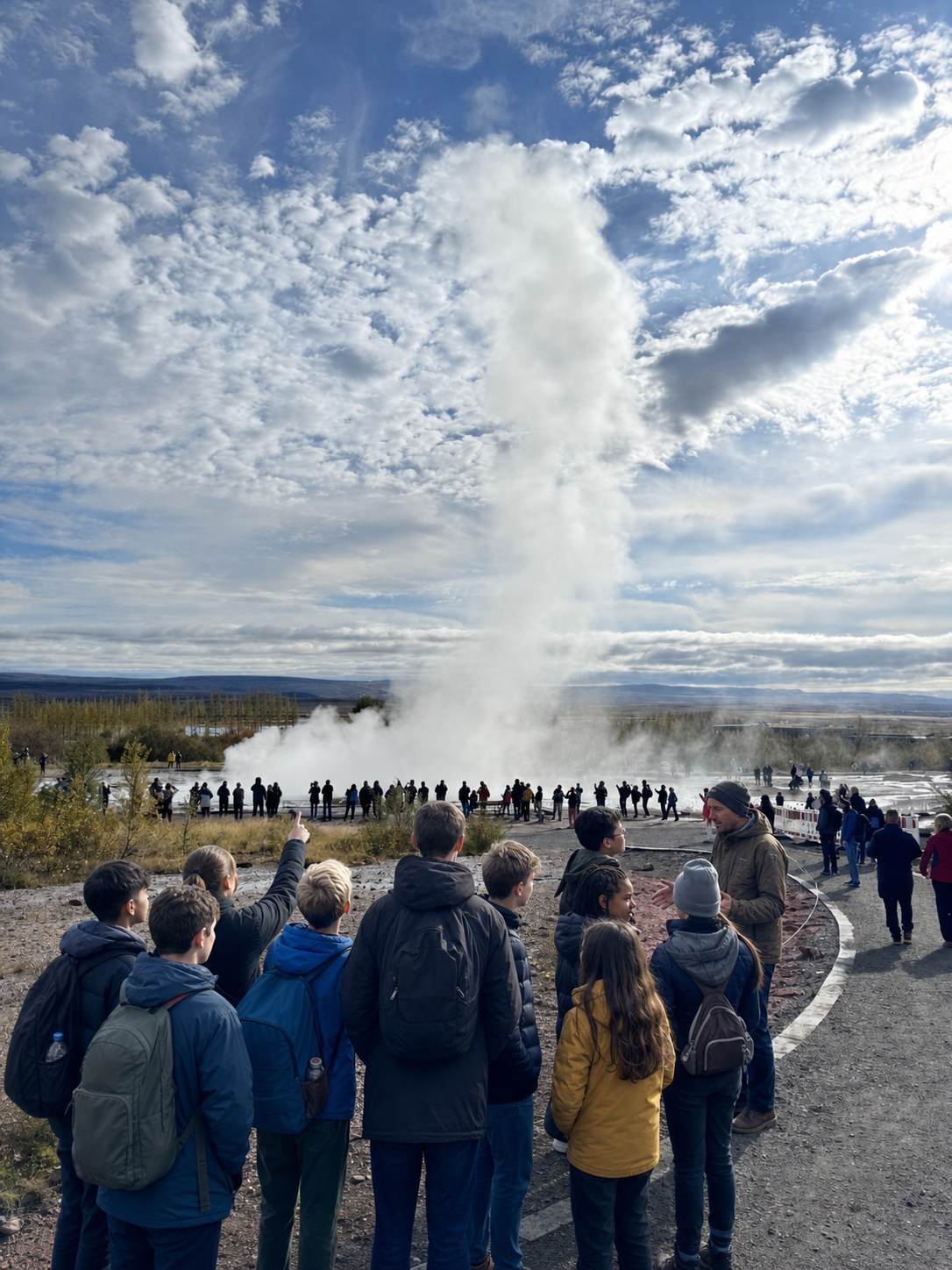Students and adults watching Strokkur geyser erupt in Iceland